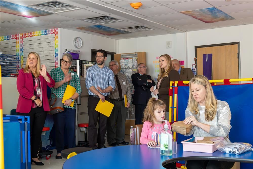  A group of seven people observe a class while a teacher and student are working.